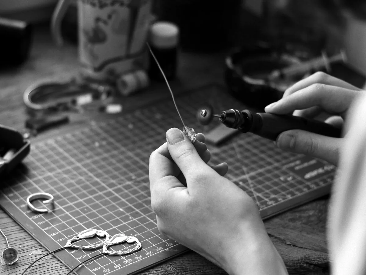 Bàn tay mài chi tiết bông tai bạc bằng máy cầm tay